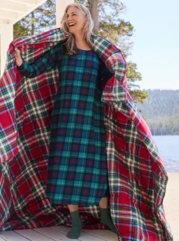 Woman wearing a green set of pajamas with a red blanket.