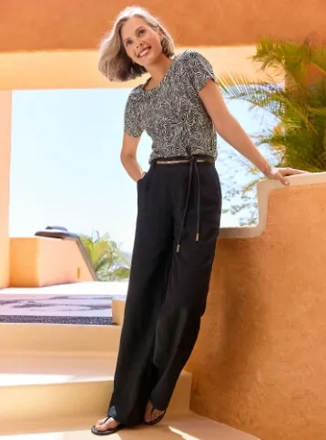 Woman wearing a black and white patterned blouse and black pants.