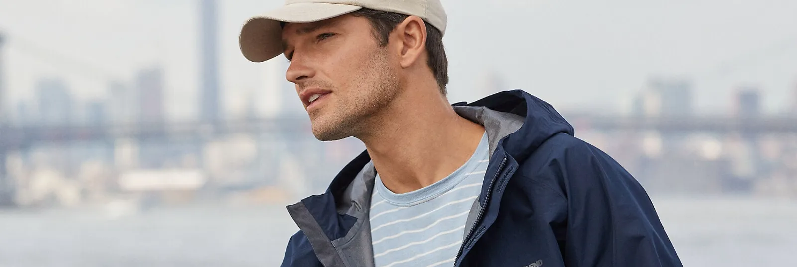 Man wearing a navy blue rain jacket and white ball cap.