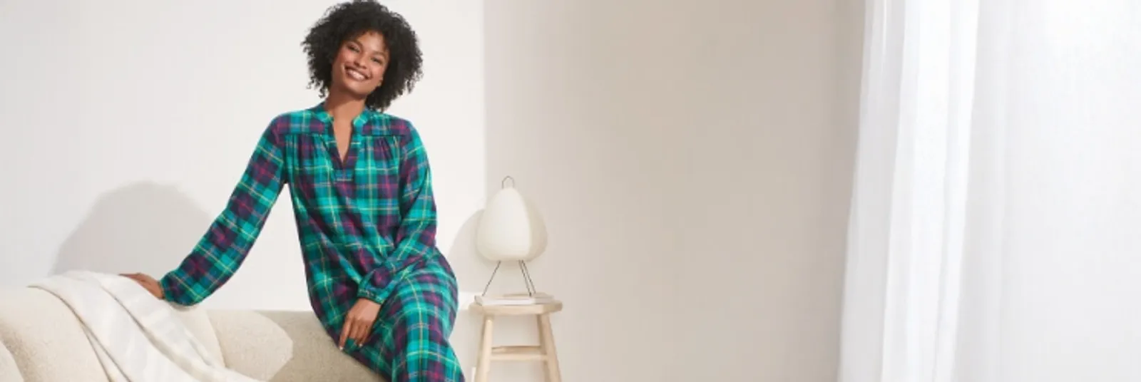 Woman wearing a green, navy blue and red flannel night gown.