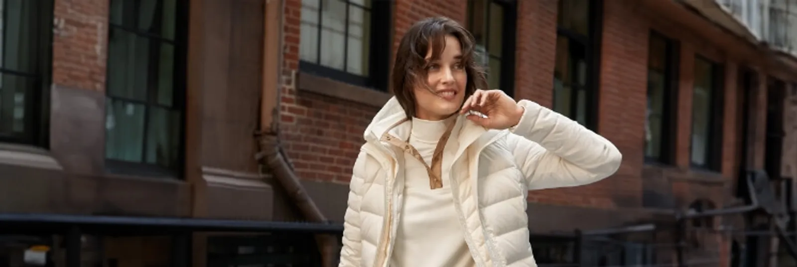 Woman wearing a white puffer jacket over a layerd white turtleneck and fleece.
