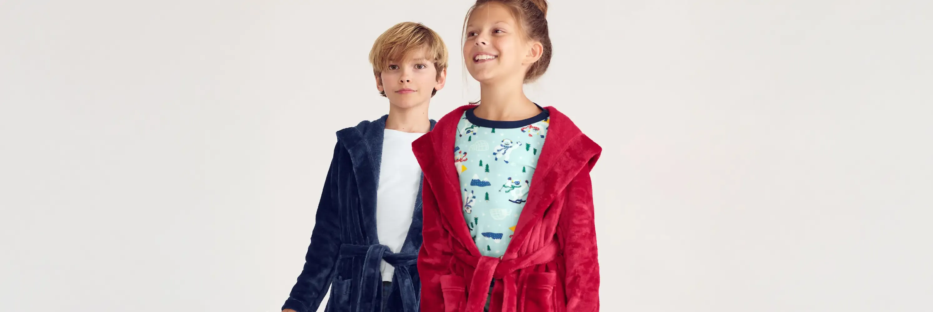 Boy and girl wearing navy and red hooded bathrobes.