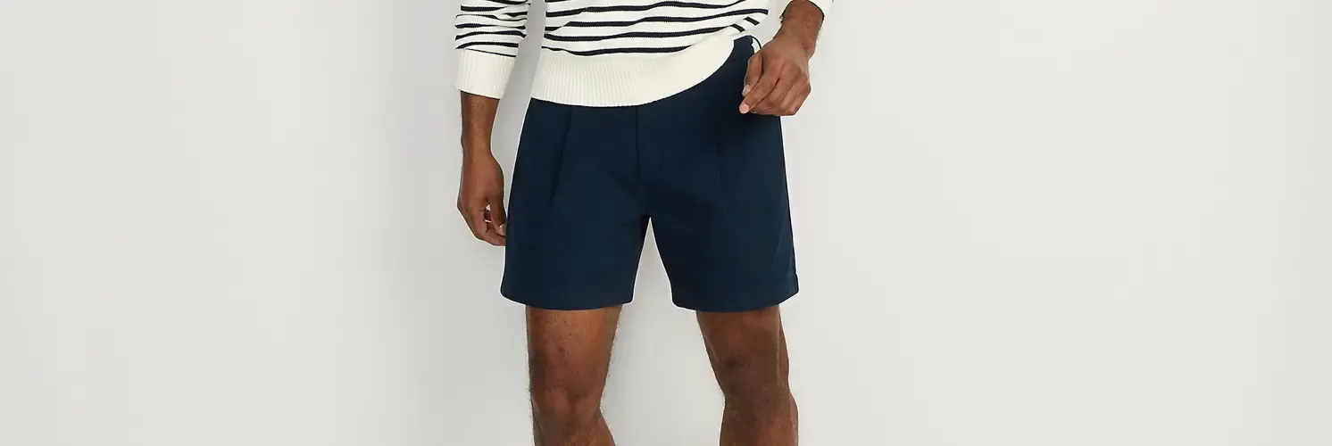 Man wearing a white and navy blue striped sweater and navy blue shorts.
