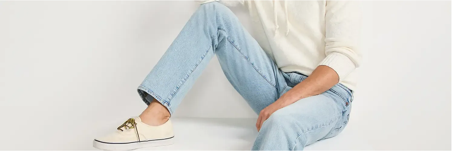 Person sitting down wearing light blue jeans and a cream-colored sweatshirt.