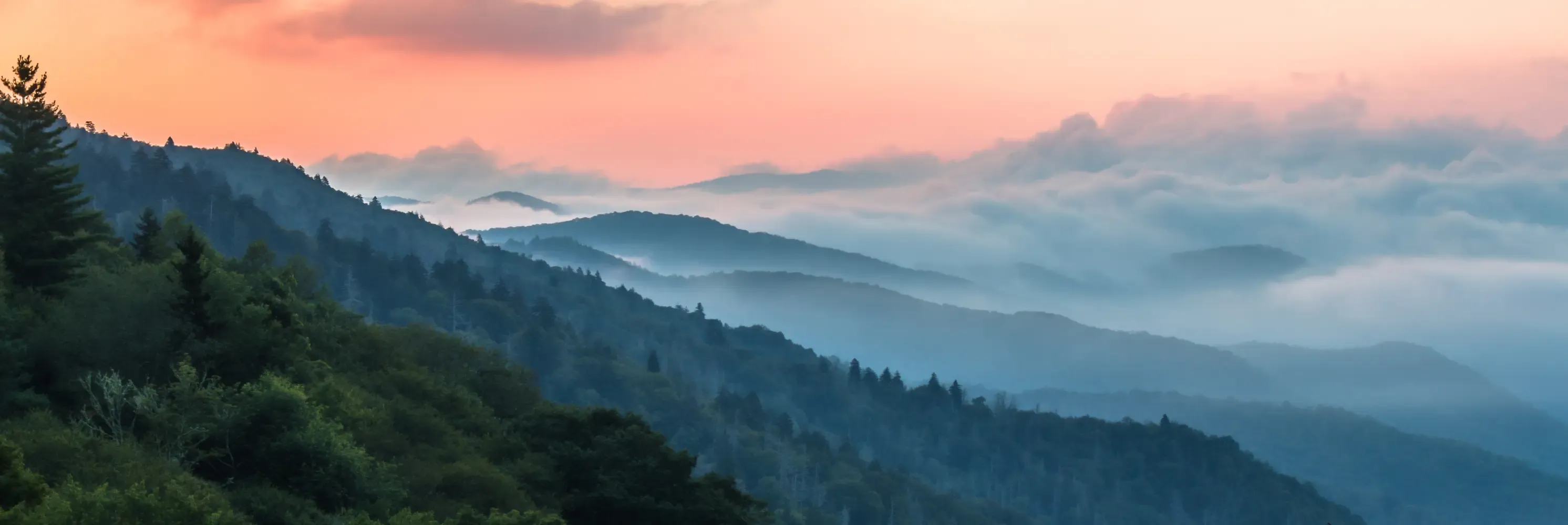 Misty mountain ridges covered in fog at dawn.