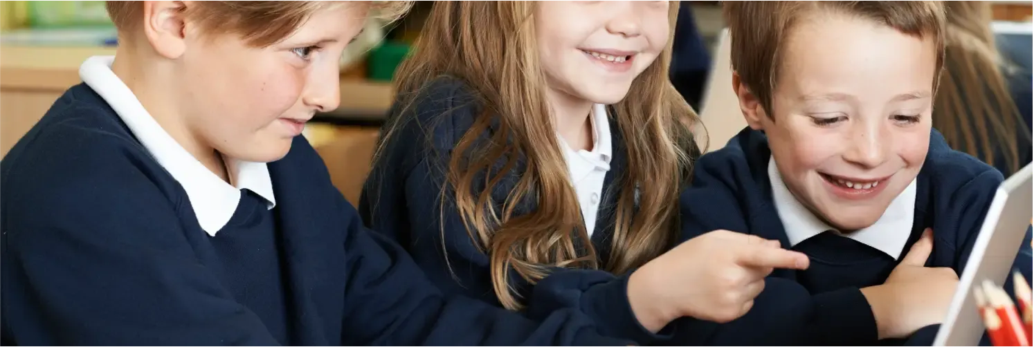 Three children wearing navy blue school uniforms with white collars