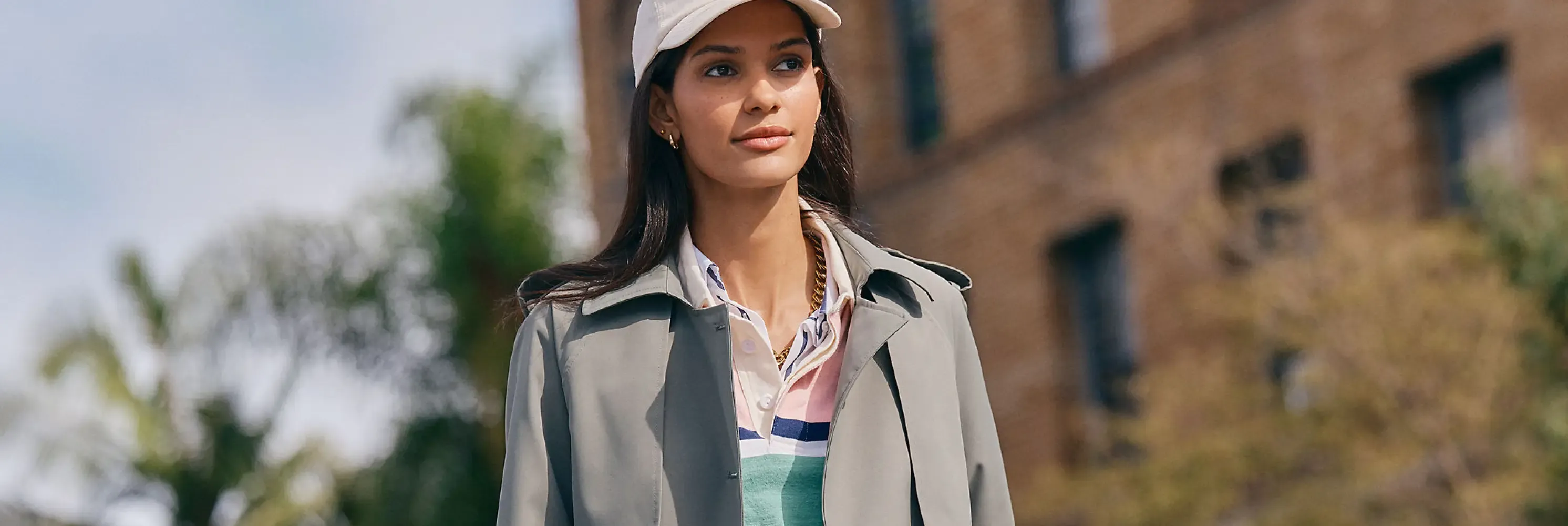Woman wearing a beige jacket over a striped rugby shirt.