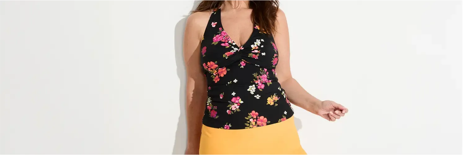Woman wearing a black tankini top with pink floral prints, paired with a yellow skirt.