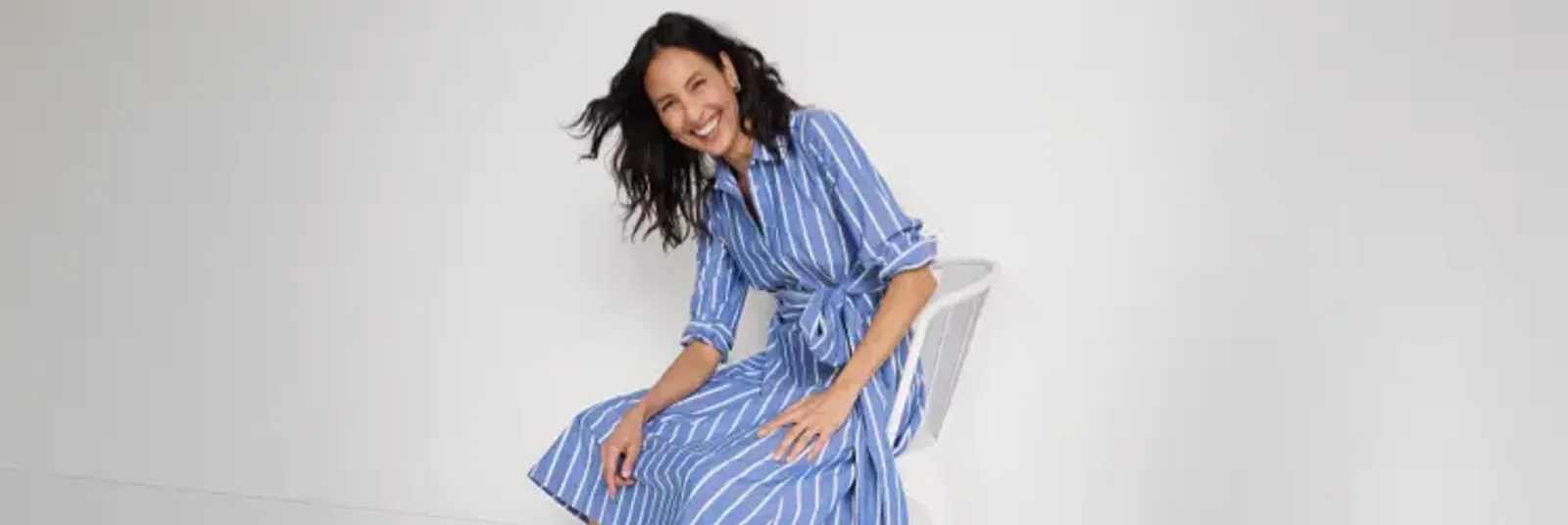 Woman wearing a blue and white striped shitr dress.