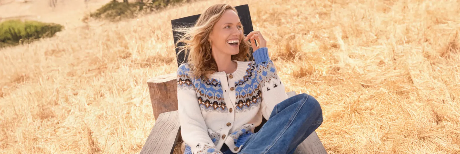 Woman in white and blue pattern cardigan sitting outdoors.
