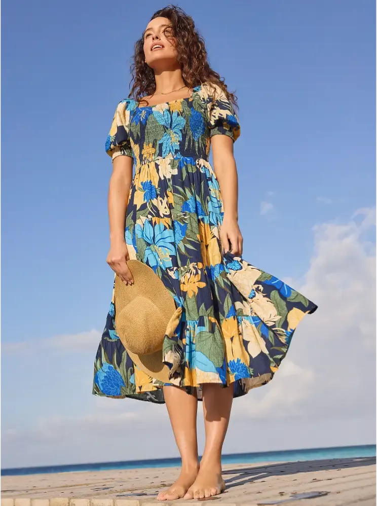 A woman wearing a navy blue floral midi dress with short puff sleeves.