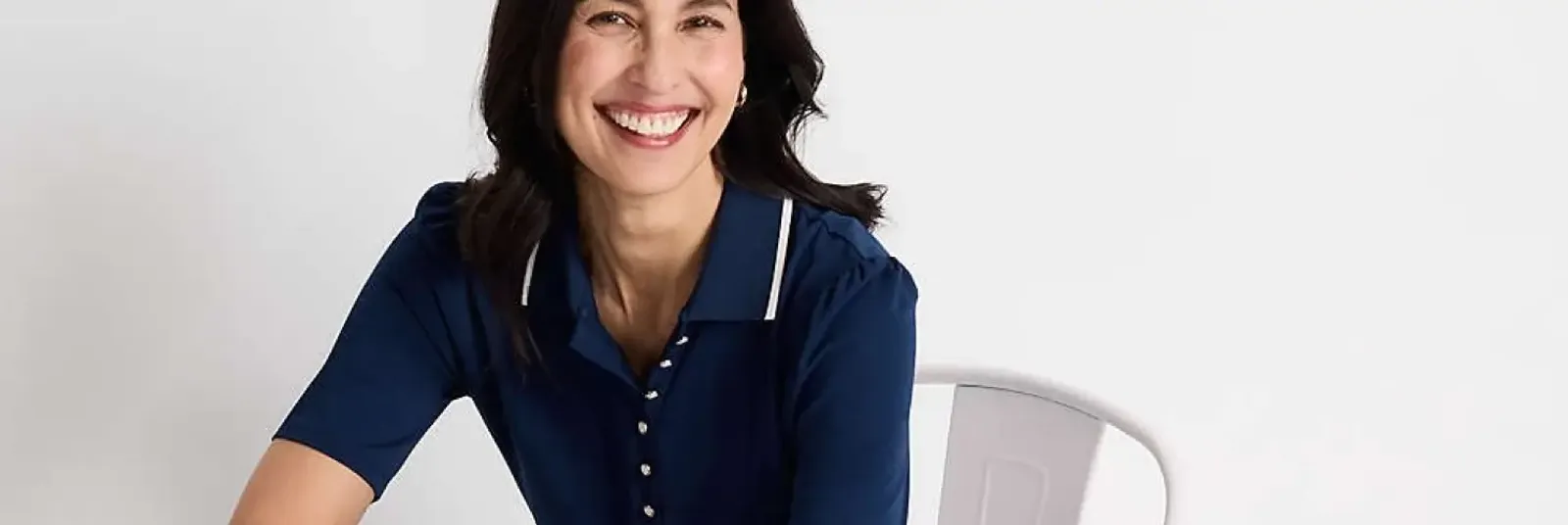 Woman wearing a short-sleeve navy blue polo shirt with white trim and buttons.