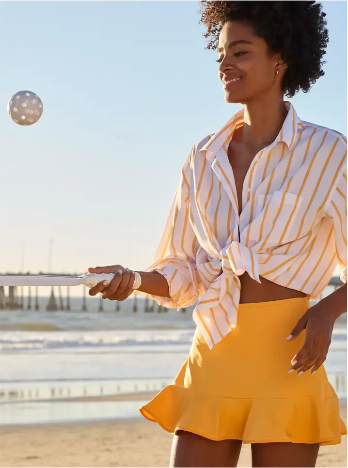 Woman wearing a yellow and white striped shirt tied at the waist, and a yellow ruffle skirt.
