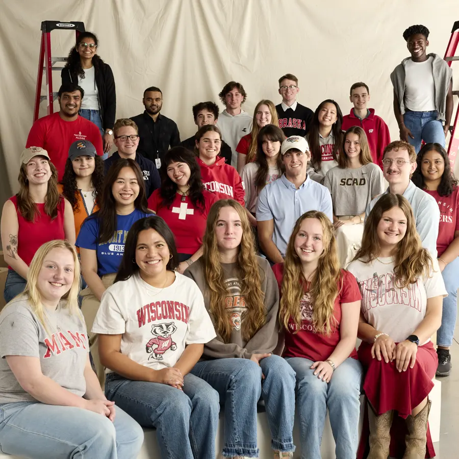 A woman resting her head on her hand smiling by a Lands&rsquo; End shipping box with spools of thread on shelves in the background.